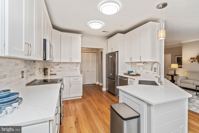 kitchen with sink, decorative light fixtures, white cabinets, and appliances with stainless steel finishes