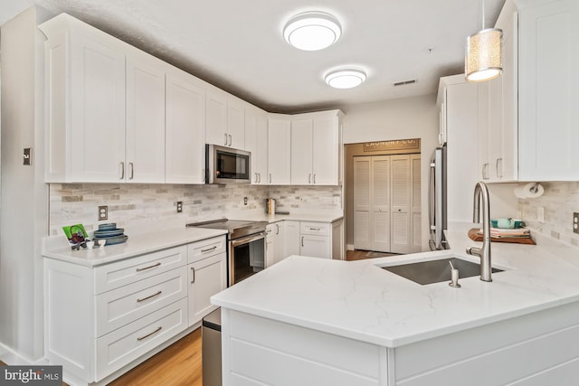 kitchen with white cabinetry, appliances with stainless steel finishes, and kitchen peninsula