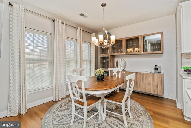 dining area with an inviting chandelier and light hardwood / wood-style flooring