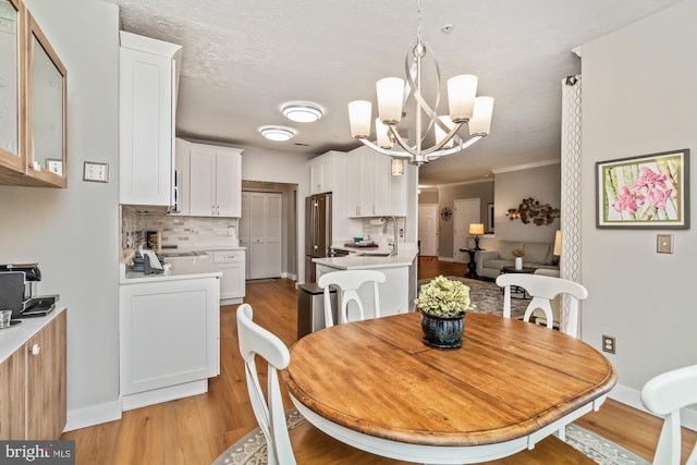 dining room with a chandelier, sink, light hardwood / wood-style flooring, and a textured ceiling