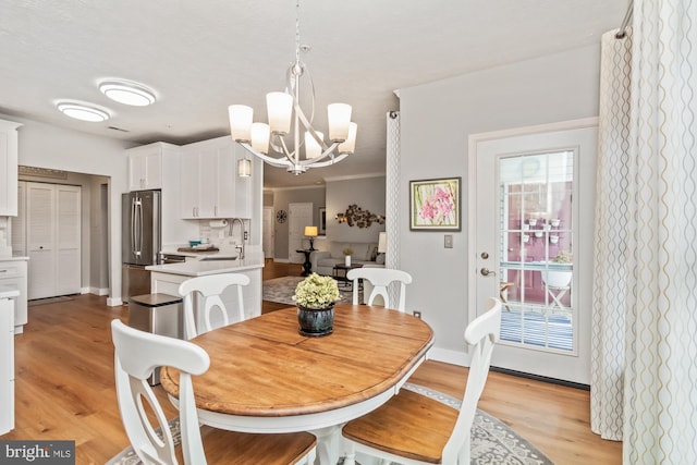 dining space featuring crown molding, light wood-type flooring, and a chandelier