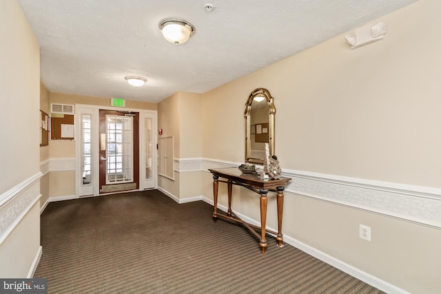 entrance foyer featuring a textured ceiling and dark carpet