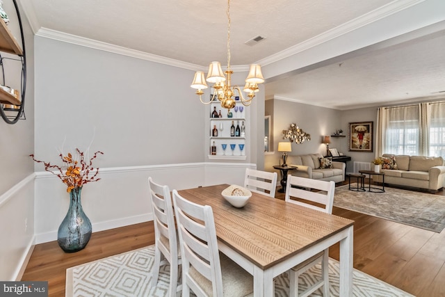 dining area featuring hardwood / wood-style flooring, ornamental molding, and a chandelier