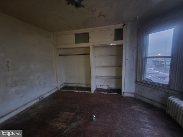 unfurnished bedroom featuring radiator heating unit and dark hardwood / wood-style floors