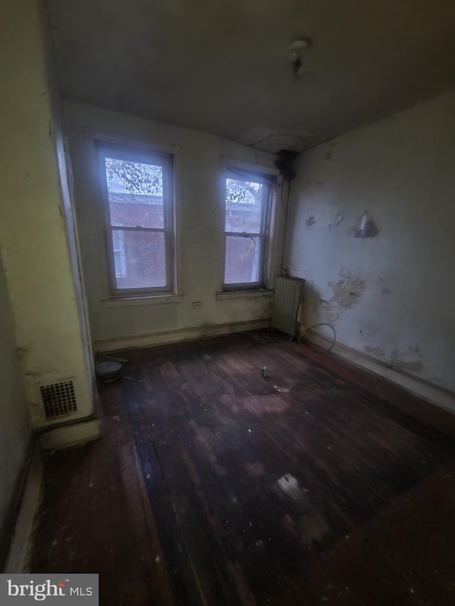 unfurnished room featuring radiator and dark hardwood / wood-style flooring