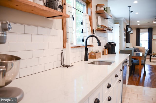 kitchen with pendant lighting, sink, ornamental molding, white cabinets, and light tile patterned flooring