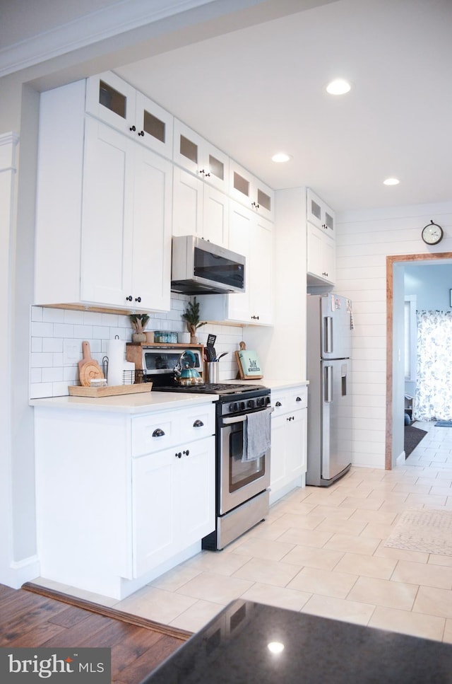 kitchen with backsplash, appliances with stainless steel finishes, and white cabinets