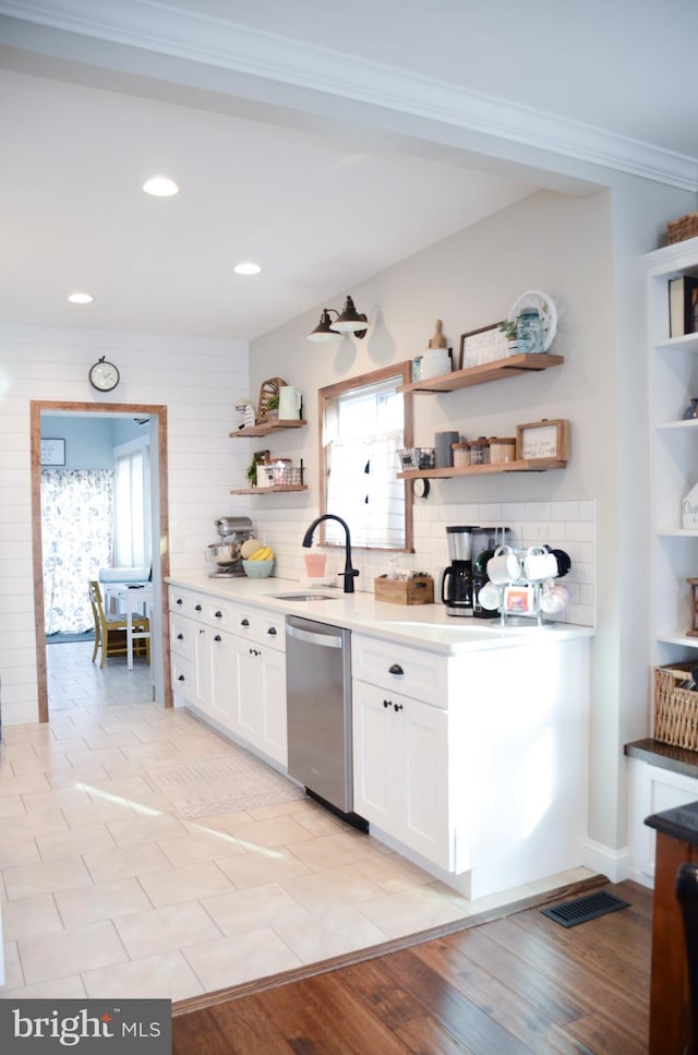 kitchen with stainless steel dishwasher, decorative backsplash, sink, light wood-type flooring, and white cabinetry