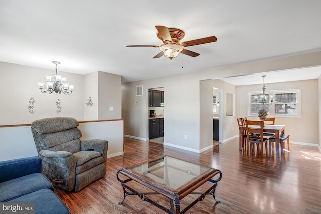 living room with dark hardwood / wood-style flooring and ceiling fan with notable chandelier