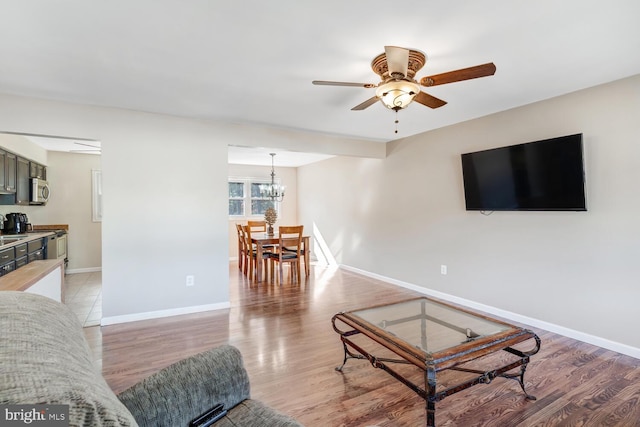 living room featuring hardwood / wood-style flooring and ceiling fan with notable chandelier