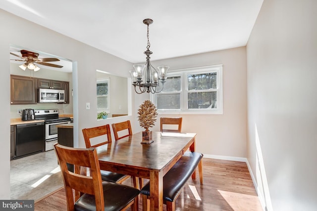 dining area with ceiling fan with notable chandelier and light hardwood / wood-style flooring