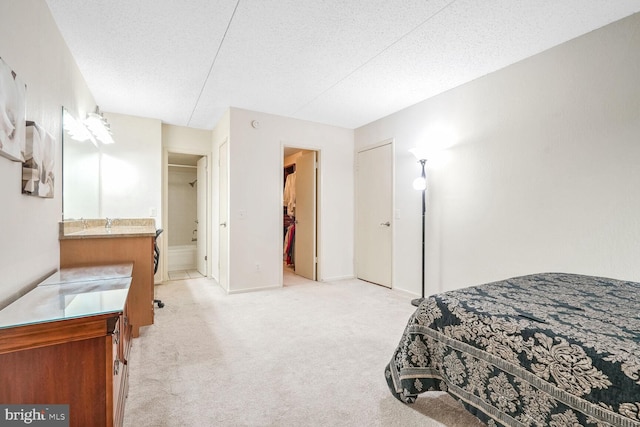 carpeted bedroom featuring a walk in closet, connected bathroom, a closet, and a textured ceiling