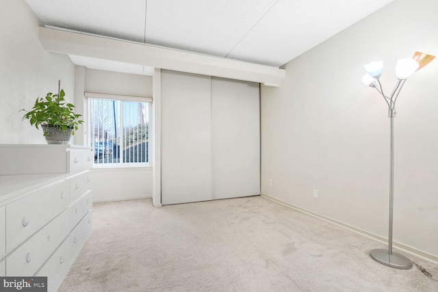 unfurnished bedroom featuring light colored carpet and a closet