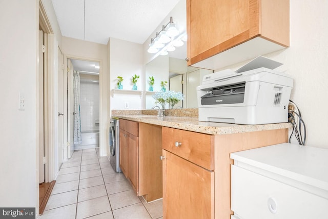 kitchen with washer / clothes dryer, light tile patterned flooring, sink, and a textured ceiling