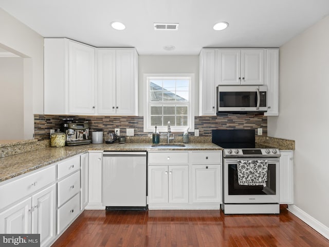 kitchen with sink, dark wood-type flooring, stainless steel appliances, white cabinets, and stone countertops