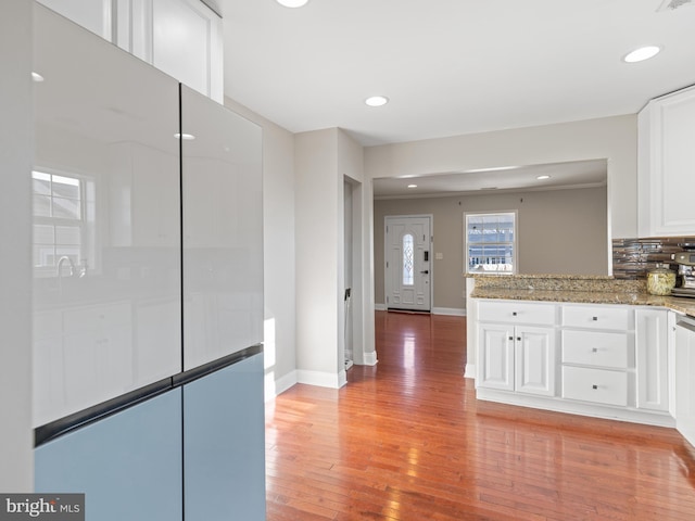 kitchen featuring tasteful backsplash, light hardwood / wood-style flooring, white cabinets, and stone counters