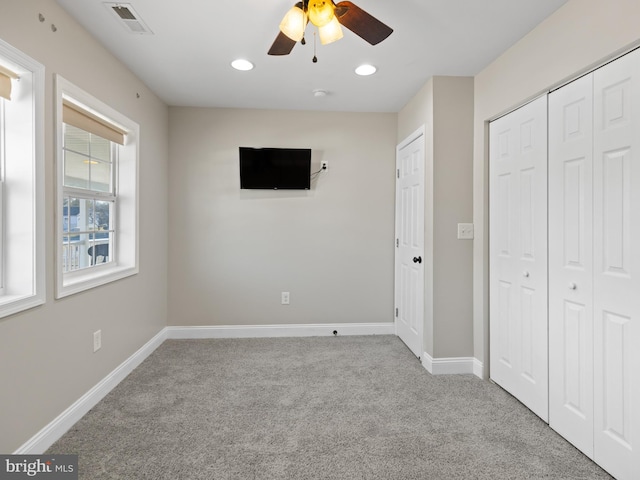 unfurnished bedroom with light colored carpet, ceiling fan, and a closet