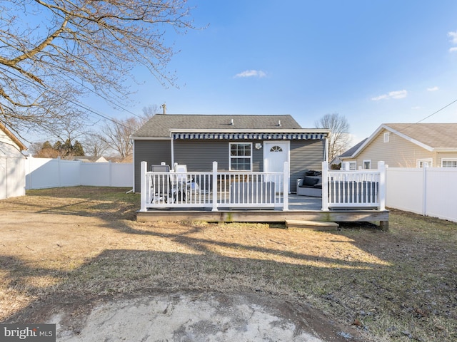 rear view of house featuring a wooden deck and a lawn