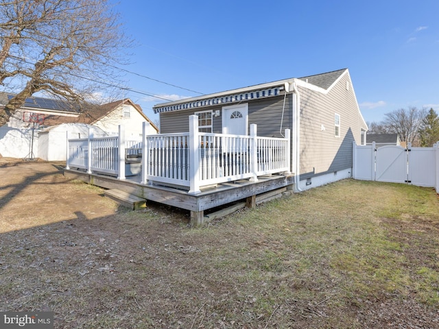 rear view of property with a wooden deck and a lawn