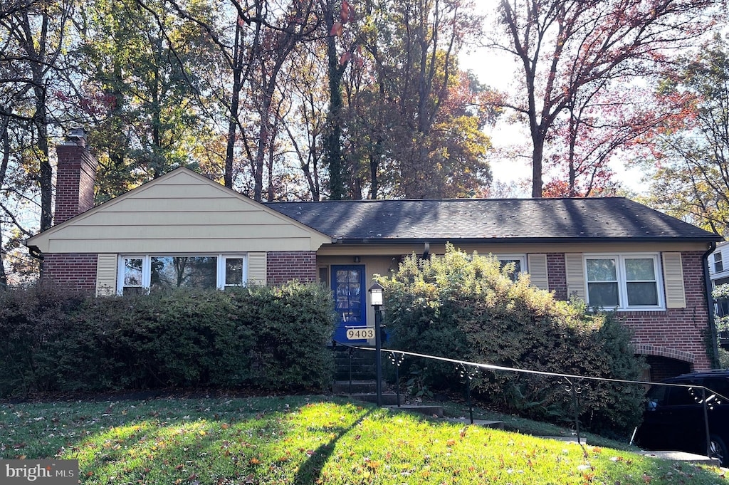 view of front of house featuring brick siding, a chimney, and a front lawn