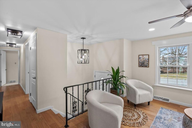 sitting room featuring ceiling fan with notable chandelier and light hardwood / wood-style floors