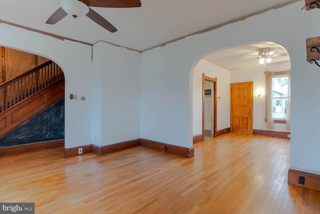 264 S Main St, Pleasant Gap, PA 16823 - empty room featuring a ceiling fan, stairs, light wood-style floors, arched walkways, and baseboards