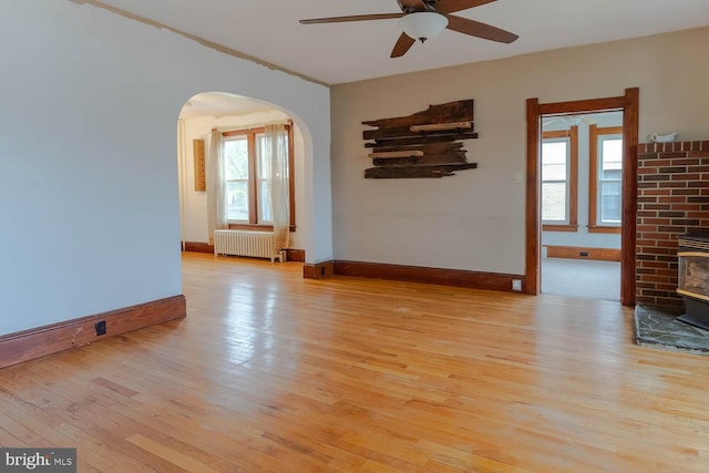 264 S Main St, Pleasant Gap, PA 16823 - unfurnished room featuring ceiling fan, arched walkways, a wood stove, radiator, and wood-type flooring