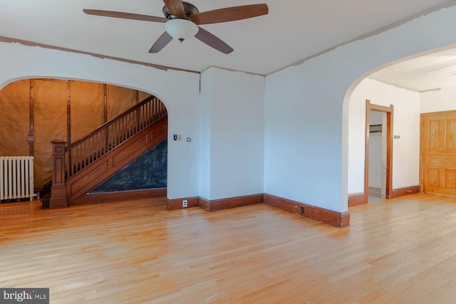 264 S Main St, Pleasant Gap, PA 16823 - unfurnished living room featuring radiator heating unit, baseboards, wood finished floors, and arched walkways