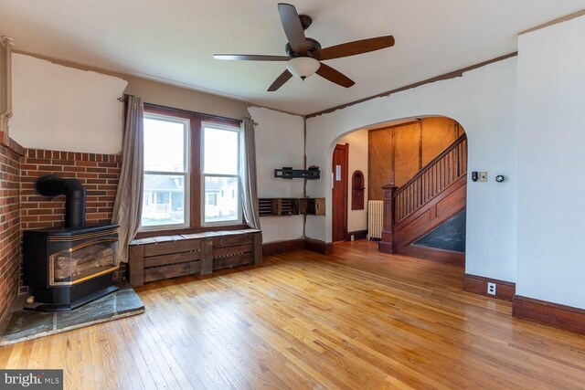 264 S Main St, Pleasant Gap, PA 16823 - unfurnished living room with hardwood / wood-style flooring, ceiling fan, arched walkways, a wood stove, and radiator