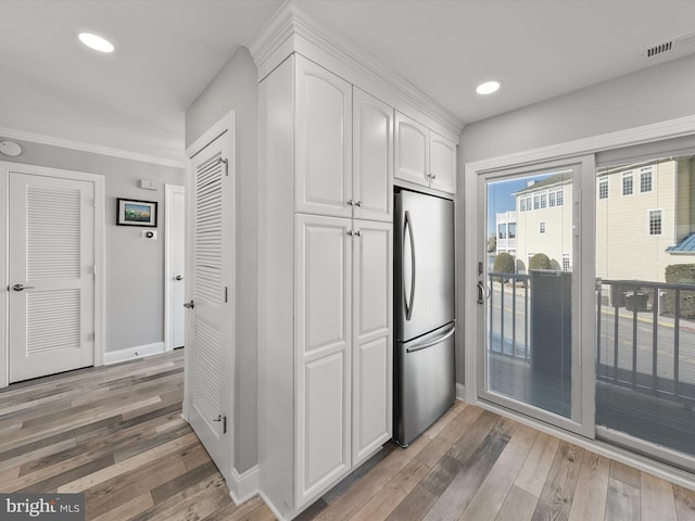 kitchen featuring white cabinetry, stainless steel fridge, crown molding, and light wood-type flooring