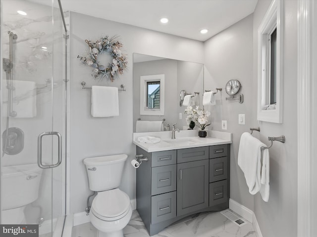 bathroom featuring vanity, a shower with shower door, and toilet