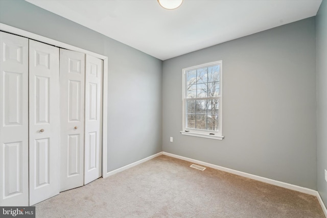 unfurnished bedroom with a closet and light carpet