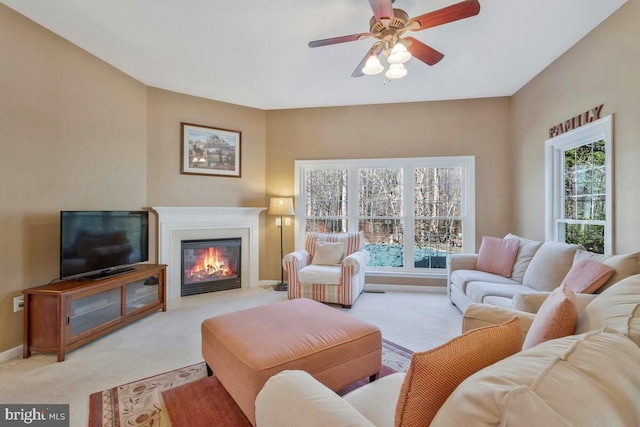 living area with baseboards, a glass covered fireplace, a wealth of natural light, and light colored carpet