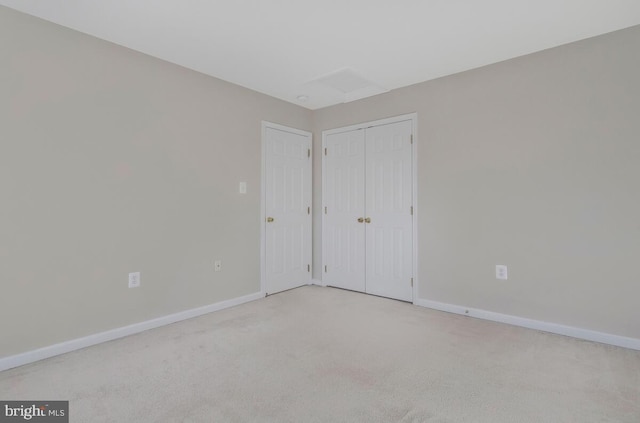 unfurnished bedroom with baseboards, a closet, and light colored carpet