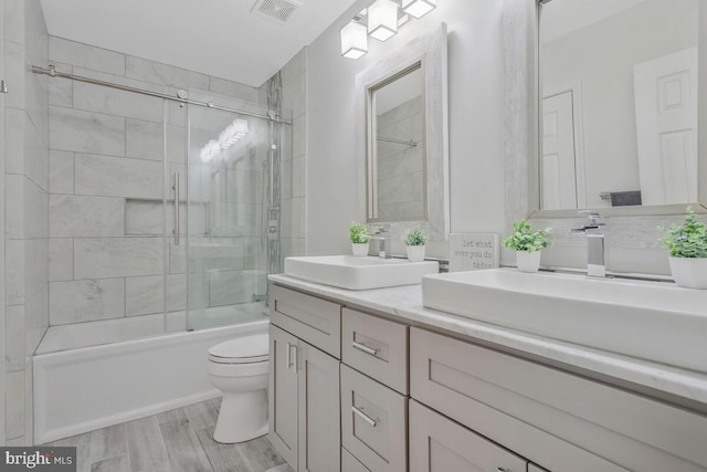 bathroom featuring shower / bath combination with glass door, visible vents, a sink, and wood finished floors