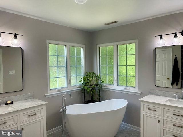 full bathroom featuring a freestanding tub, two vanities, a sink, and visible vents