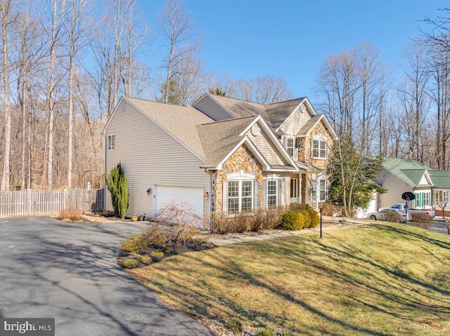 view of front of home featuring stone siding, fence, driveway, and a front lawn