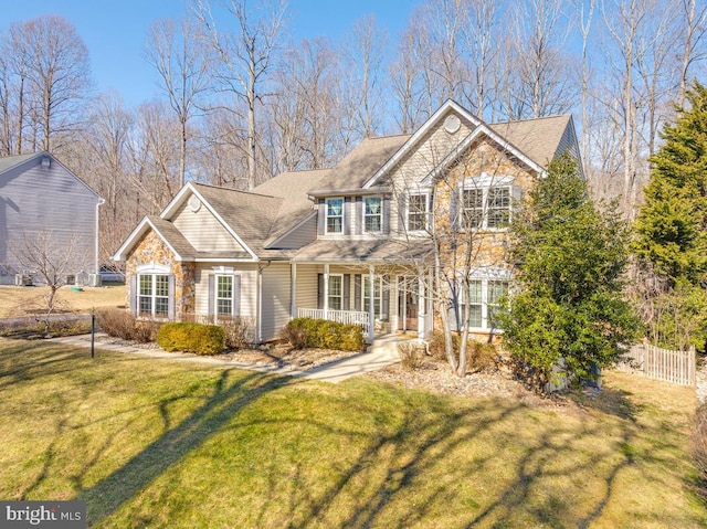 view of front of house featuring stone siding, fence, a porch, and a front yard