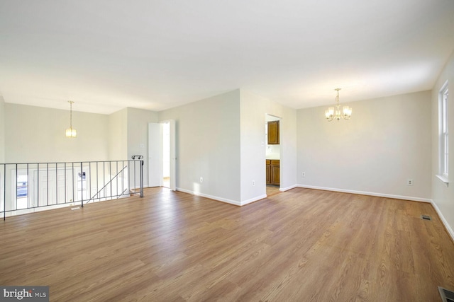 empty room with light hardwood / wood-style floors and a notable chandelier