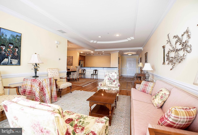 living room with crown molding, wood-type flooring, and a raised ceiling