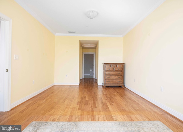 empty room with ornamental molding and light hardwood / wood-style floors