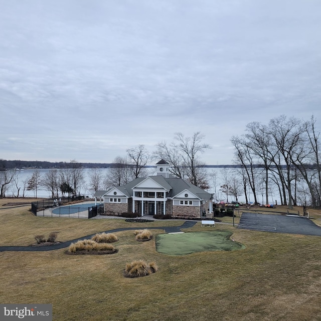 exterior space featuring a water view, a pool, and a lawn