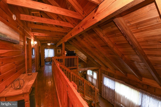 hallway with vaulted ceiling with beams, dark wood-type flooring, wooden ceiling, and wood walls