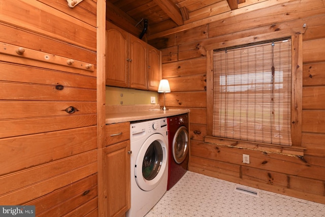 laundry room featuring cabinets, washing machine and clothes dryer, and wood walls