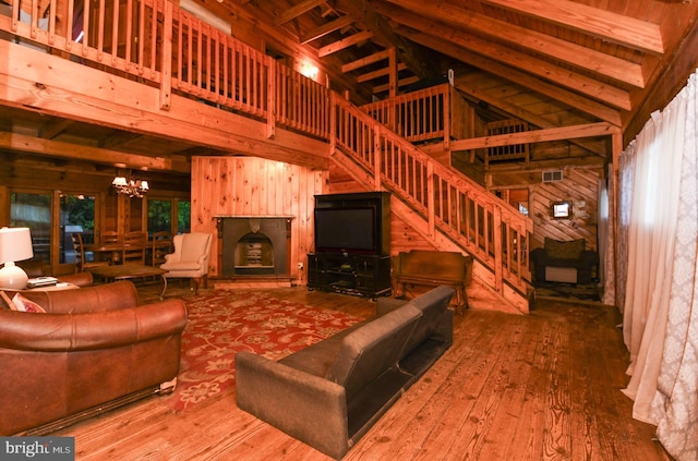 unfurnished living room featuring hardwood / wood-style floors, a notable chandelier, a high ceiling, and wood walls