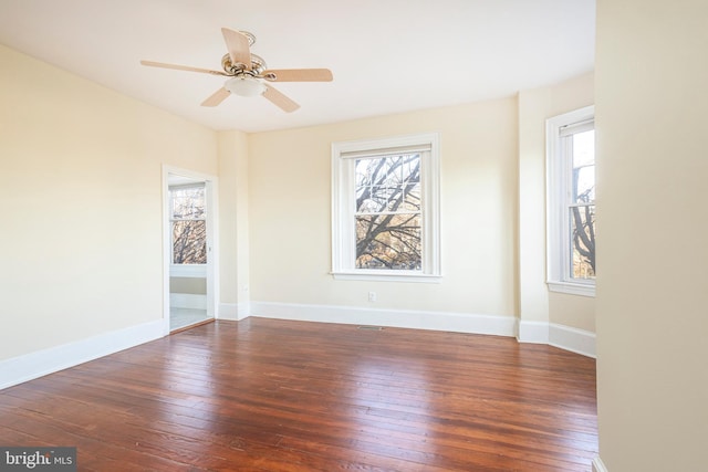 empty room featuring ceiling fan, a healthy amount of sunlight, and dark hardwood / wood-style flooring