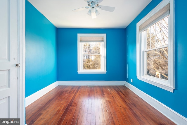 empty room with plenty of natural light, dark wood-type flooring, and ceiling fan