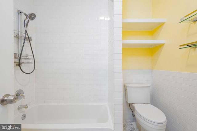 bathroom featuring tiled shower / bath combo, tile walls, and toilet