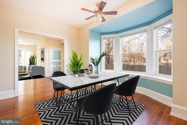 dining area with dark wood-type flooring and ceiling fan