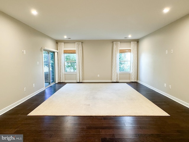 spare room with dark hardwood / wood-style flooring and plenty of natural light